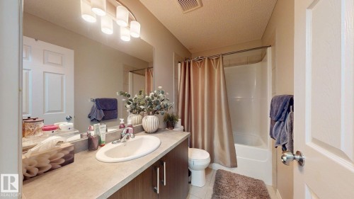 Bathroom featuring a vanity with an integrated sink, a large mirror, and a combination shower and bathtub - 1275 Chappelle Boulevard, Edmonton, AB 