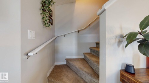 Carpeted staircase with wall-mounted handrails and neutral wall finishes - 1275 Chappelle Boulevard, Edmonton, AB 