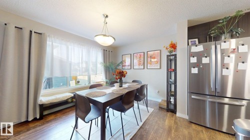 The dining area features hard flooring, a large window, and a ceiling light fixture - 1275 Chappelle Boulevard, Edmonton, AB 