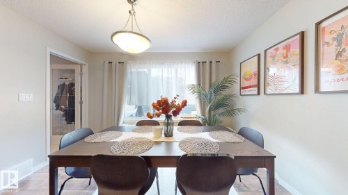 Well-lit dining area featuring a dark wood dining table, neutral wall paint, and a window with curtains - 1275 Chappelle Boulevard, Edmonton, AB 