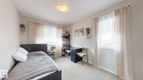 The room features a neutral color palette, carpeted flooring, and windows with curtains allowing for natural light - 1275 Chappelle Boulevard, Edmonton, AB 