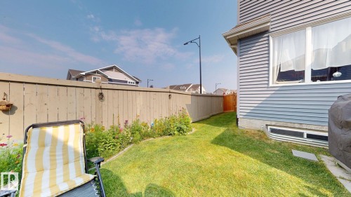 The property includes a fenced yard with a well-maintained lawn and a variety of colorful flowers along the fence line - 1275 Chappelle Boulevard, Edmonton, AB 