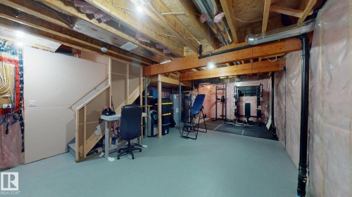 Spacious unfinished basement with exposed wooden beams, a staircase, and ample room for storage or customization - 1275 Chappelle Boulevard, Edmonton, AB 