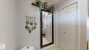 Entryway featuring a full-length mirror with a dark frame, white paneled bifold doors, and light-colored tile flooring - 1275 Chappelle Boulevard, Edmonton, AB 
