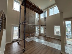 Two-story interior with a prominent accent wall featuring decorative paneling, wood-finish flooring, recessed lighting, and multiple windows - 