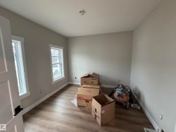 Neutral gray wall paint with white trim, wood-finish flooring, and dual windows - 