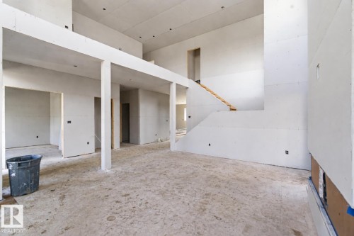 An expansive interior space, currently under construction, features high ceilings and a visible staircase - 33 Harley Way Nw, Spruce Grove, AB - Indoor Photo Showing Other Room