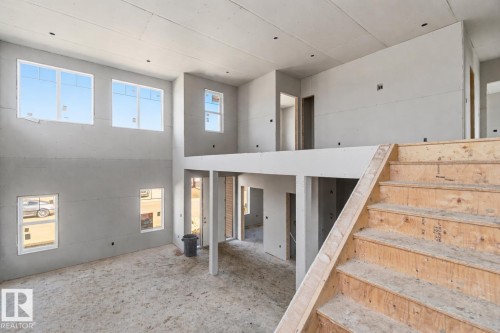 Interior space featuring a wooden staircase, light-colored walls, and windows providing natural light - 33 Harley Way Nw, Spruce Grove, AB - Indoor Photo Showing Other Room