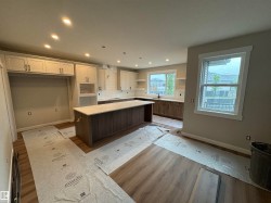 Modern kitchen featuring wood-finish flooring, recessed lighting, and a spacious island with a light-toned countertop - 