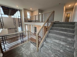 Multi-level interior featuring a carpeted staircase, wood-finish flooring, recessed lighting, and horizontal metal balusters with wood-finish handrails - 