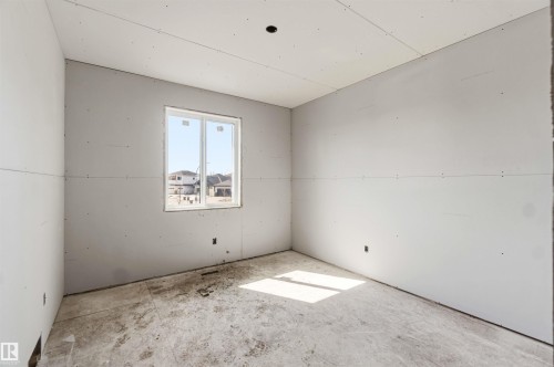 Unfinished room with a window, providing natural light, and a view of the surrounding neighborhood - 33 Harley Way Nw, Spruce Grove, AB - Indoor