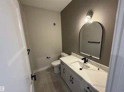 Bathroom featuring a white vanity with black hardware, a black faucet, and a large arched mirror - 