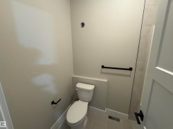 Modern bathroom featuring a white toilet, light gray painted walls, and coordinated gray floor tiling - 