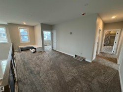 Spacious loft area featuring neutral-toned carpeting, ample natural light from multiple windows, and a built-in window bench - 