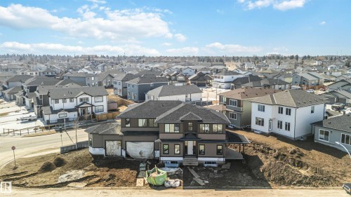 The property features a multi-story design with a dark gray roof and a light brown exterior, situated on a sloped lot - 33 Harley Way Nw, Spruce Grove, AB - Outdoor