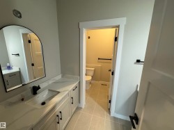 Bathroom featuring a wide vanity with a rectangular undermount sink, a white countertop, and light gray cabinetry - 
