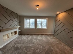 Spacious room featuring accent walls with geometric paneling, a fireplace with a wood mantel, and integrated shelving - 