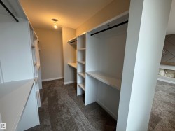 Walk-in closet featuring built-in white shelving, integrated hanging rods, recessed lighting, and carpet flooring - 