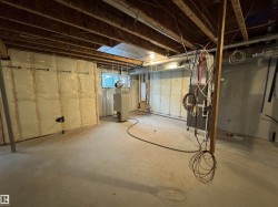 Unfinished basement space featuring exposed wood joists and concrete flooring - 
