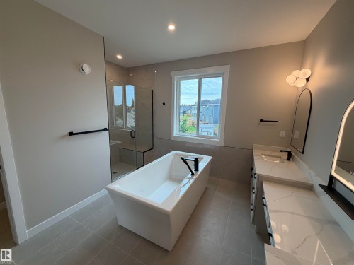 Freestanding soaking tub with a floor-mounted faucet, walk-in shower with glass enclosure, dual vanity with undermount sinks, and tile flooring - 33 Harley Way, Spruce Grove, AB - Indoor Photo Showing Other Room
