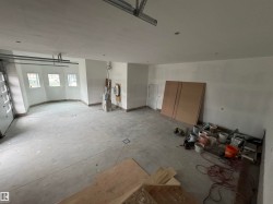 Spacious garage featuring a concrete floor, white walls, three windows with white frames, and a white garage door - 