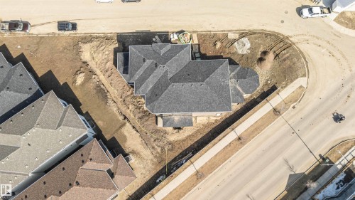 The property features a dark gray shingled roof and is situated on a corner lot with an adjacent sidewalk - 33 Harley Way, Spruce Grove, AB - 