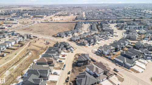 Aerial view showcasing a residential neighborhood with numerous properties featuring gray roofs, surrounded by streets and open land - 33 Harley Way, Spruce Grove, AB - Outdoor With View