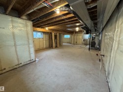 Expansive unfinished basement featuring concrete flooring, exposed ceiling joists, framed walls with insulation, multiple windows, and visible ductwork - 
