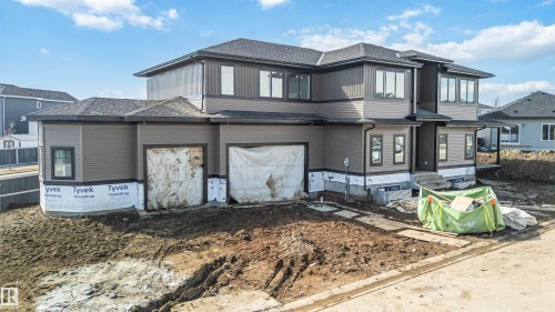 The property features a multi-level design with a dark gray shingled roof and light brown siding - 33 Harley Way Nw, Spruce Grove, AB - Outdoor