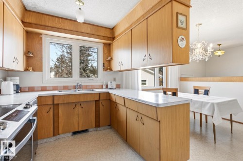 The kitchen features wood cabinetry, white countertops, and a double window above the sink - 10716 52 Avenue, Edmonton, AB - Indoor Photo Showing Kitchen With Double Sink