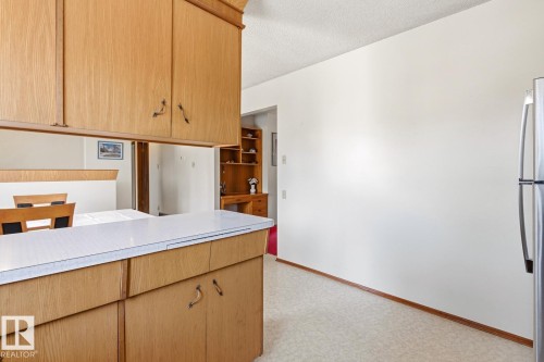 Kitchen with wood cabinetry, a white countertop, and a stainless steel refrigerator - 10716 52 Avenue, Edmonton, AB - Indoor Photo Showing Kitchen