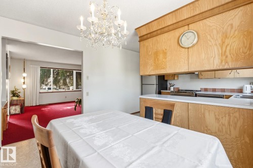 The dining area features a crystal chandelier and an open view to the living area - 10716 52 Avenue, Edmonton, AB - Indoor Photo Showing Kitchen