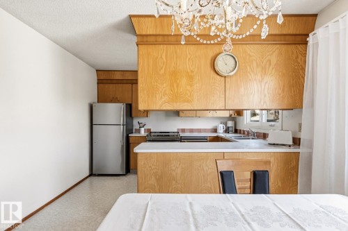Kitchen featuring wood cabinetry, stainless steel refrigerator, and a window above the sink - 10716 52 Avenue, Edmonton, AB - Indoor Photo Showing Kitchen With Double Sink