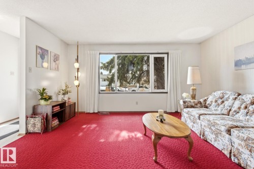 Living room featuring red carpet, a large window providing natural light, and white walls - 10716 52 Avenue, Edmonton, AB - Indoor Photo Showing Living Room