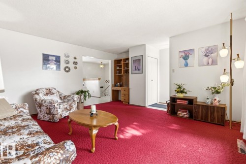 The living room features plush red carpeting, white painted walls, and a recessed entryway - 10716 52 Avenue, Edmonton, AB - Indoor Photo Showing Living Room
