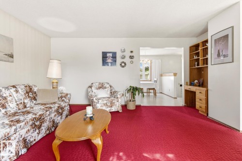Living area featuring bright red carpeting and a built-in wooden desk with shelving - 10716 52 Avenue, Edmonton, AB - Indoor Photo Showing Living Room