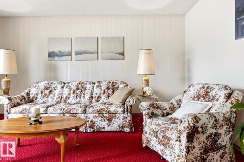 Living room featuring a bright red carpet, white textured wallpaper, and a wall with a smooth white finish - 10716 52 Avenue, Edmonton, AB - Indoor Photo Showing Living Room