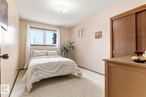 This room features a window with white curtains, a ceiling light fixture, and a closet with sliding wooden doors - 10716 52 Avenue, Edmonton, AB - Indoor Photo Showing Bedroom