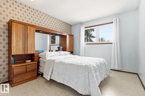 This room features a window providing natural light, light blue walls, and patterned wallpaper - 10716 52 Avenue, Edmonton, AB - Indoor Photo Showing Bedroom