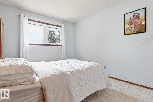 This room offers neutral colored walls, a window with a view of trees, and light-colored flooring - 10716 52 Avenue, Edmonton, AB - Indoor Photo Showing Bedroom