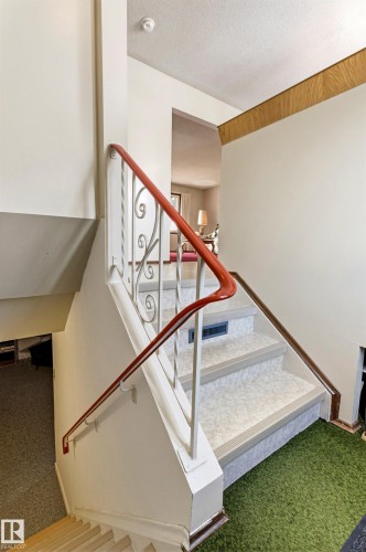 Interior staircase featuring a red and white railing, white risers, and patterned treads - 10716 52 Avenue, Edmonton, AB - Indoor Photo Showing Other Room