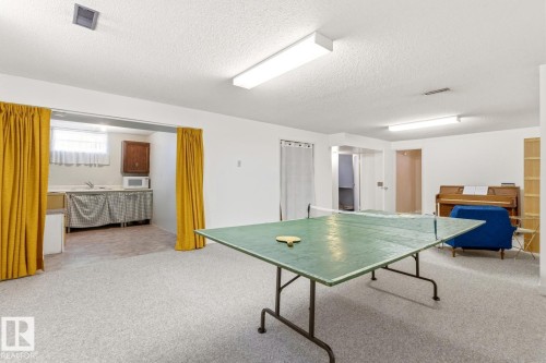 Spacious recreational area featuring light-colored carpeting, white walls, and overhead lighting - 10716 52 Avenue, Edmonton, AB - Indoor Photo Showing Other Room
