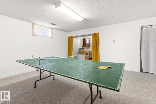 Recreational area featuring a textured carpeted floor, white walls, and a window with white curtains - 10716 52 Avenue, Edmonton, AB - Indoor Photo Showing Other Room