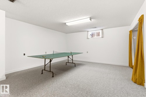 Spacious room featuring light-colored carpeting, white walls, and a window for natural light - 10716 52 Avenue, Edmonton, AB - Indoor Photo Showing Other Room
