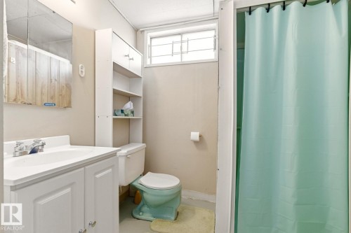 The bathroom features a white vanity with a sink and a chrome faucet, a wall-mounted medicine cabinet with a mirror, and a toilet - 10716 52 Avenue, Edmonton, AB - Indoor Photo Showing Bathroom