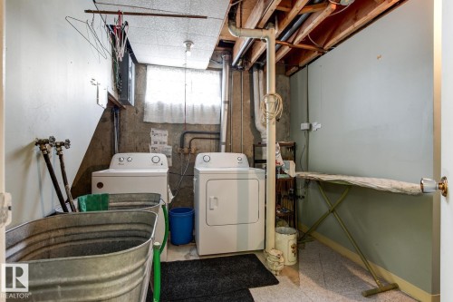 Dedicated laundry area featuring a washer and dryer, exposed ceiling joists, and a window providing natural light - 10716 52 Avenue, Edmonton, AB - Indoor Photo Showing Laundry Room