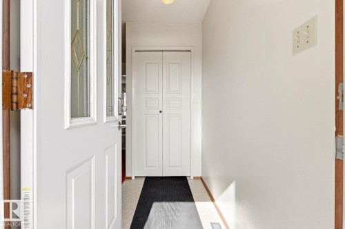 Inviting entryway featuring a white door with decorative glass inserts, light-colored flooring, and a closet with bifold doors - 10716 52 Avenue, Edmonton, AB - Indoor Photo Showing Other Room