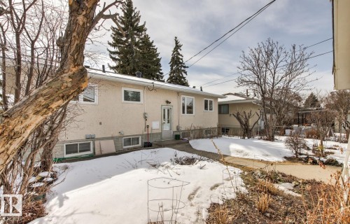 The property features a stucco exterior, a rear door with a security screen, and multiple windows - 10716 52 Avenue, Edmonton, AB - Outdoor