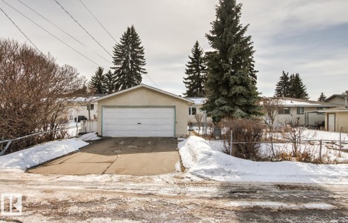 The property includes an attached garage with a concrete driveway and a fence enclosing the yard - 10716 52 Avenue, Edmonton, AB - Outdoor