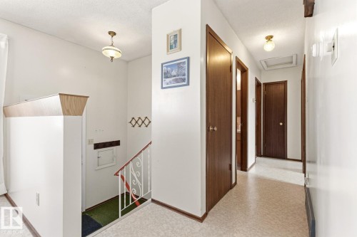 The property features a staircase with a white metal railing and a wood-capped half-wall - 10716 52 Avenue, Edmonton, AB - Indoor Photo Showing Other Room